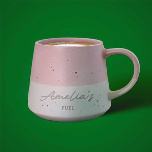 Personalised ceramic mug with a printed name design, displayed against a green background.